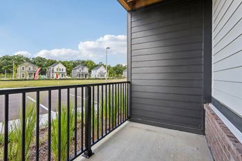 Private apartment patio at Montage West Lafayette with black railing and modern siding.